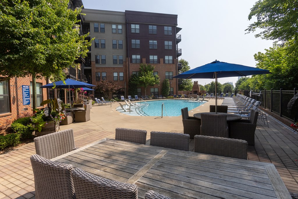 a swimming pool with lounge chairs and umbrellas in front of a building