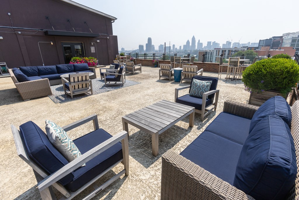 an outdoor patio with blue couches and wooden chairs with a view of the philadelphia skyline