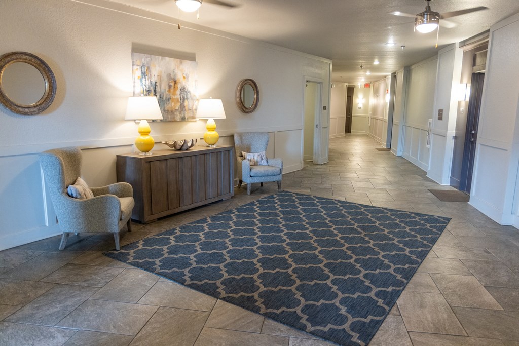 a hallway with a blue rug and two chairs