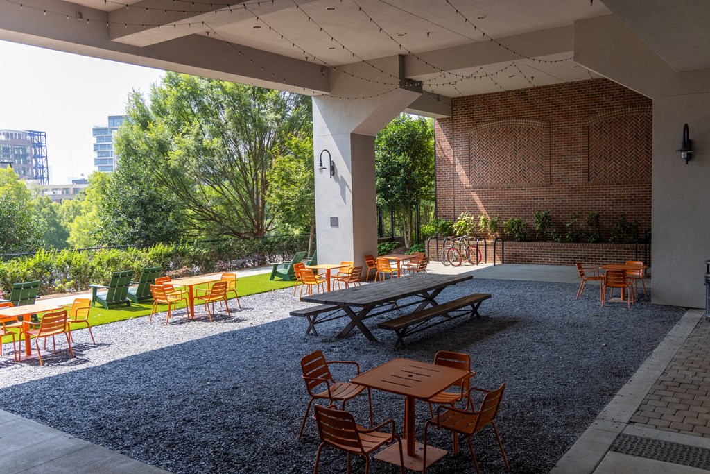 a patio with picnic tables and chairs in front of a brick wall