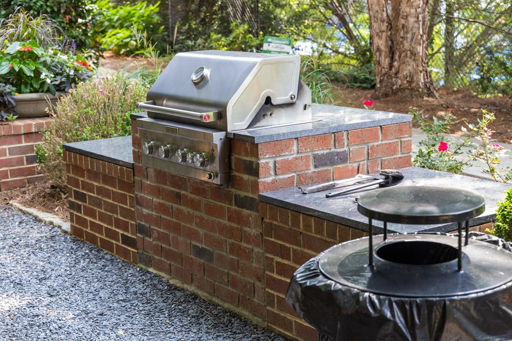 a brick outdoor kitchen with a grill and a table