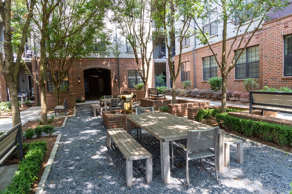 a courtyard with wooden tables and benches in front of a brick building