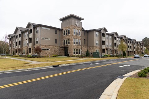 A large apartment complex with a parking lot in front.