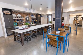 a long table with wooden chairs and blue stools in front of a long counter with a