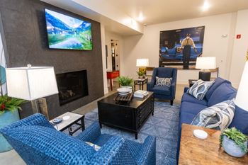 a living room with blue couches and chairs and a fireplace with a tv on the wall
