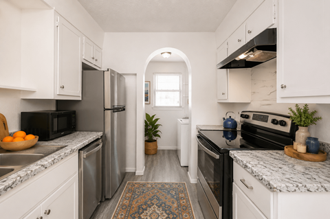 A kitchen with white cabinets and a marble countertop.