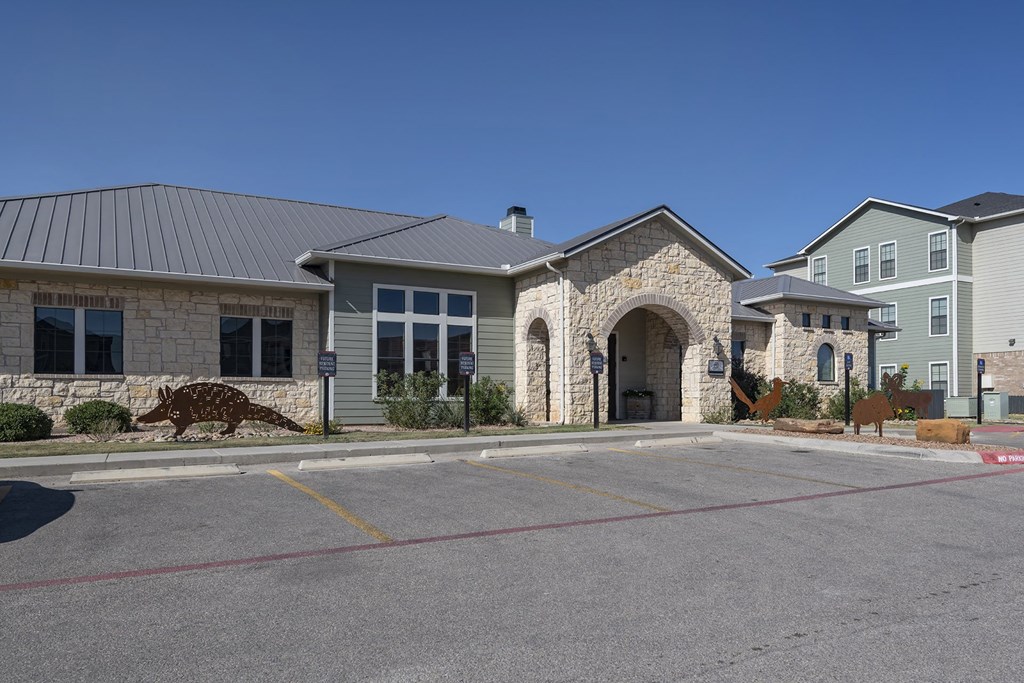 A stone building with a grey roof and a parking lot in front.