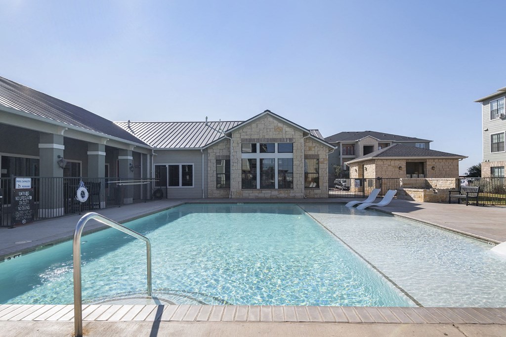 A swimming pool in front of a building with a metal fence.