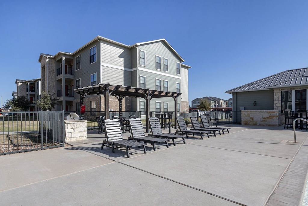 A row of lounge chairs are set up on a patio in front of a building.