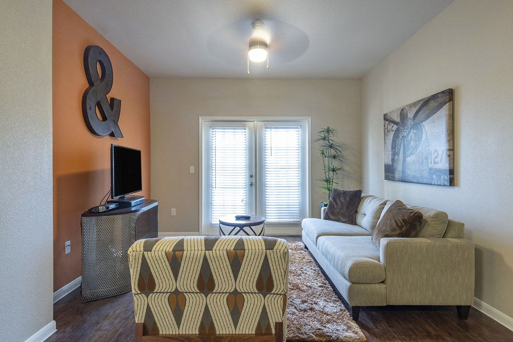 A living room with a couch, a chair, a television, and a ceiling fan.