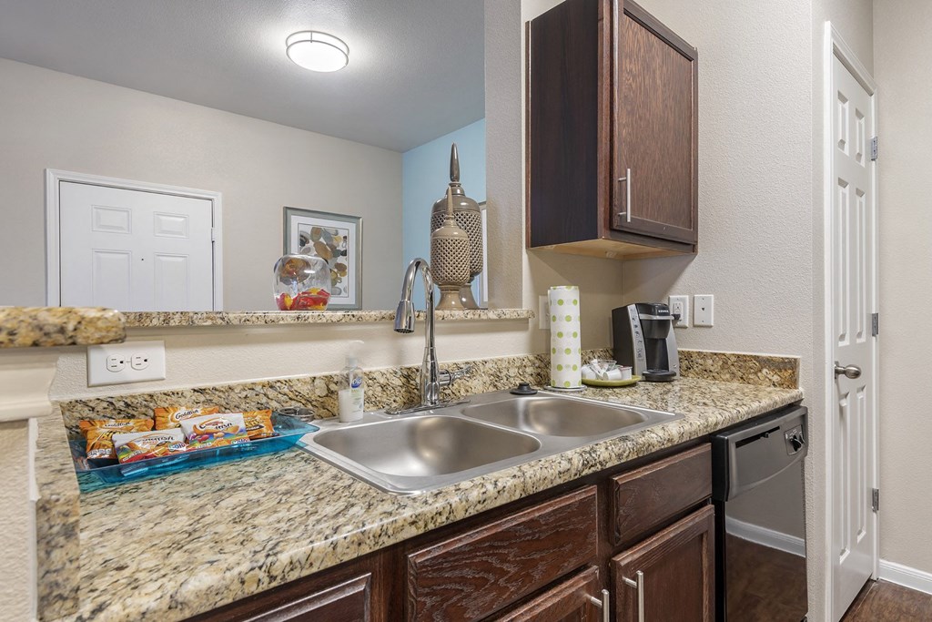 A kitchen with granite countertops and wooden cabinets.