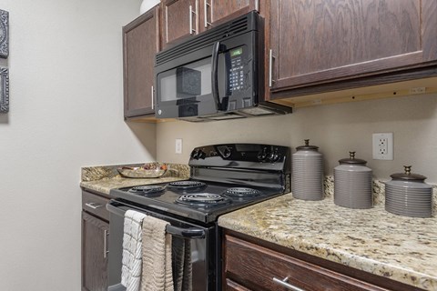 A black microwave is mounted above a black stove in a kitchen.