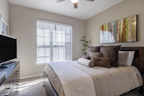 A bedroom with a bed, a television, and a painting on the wall.