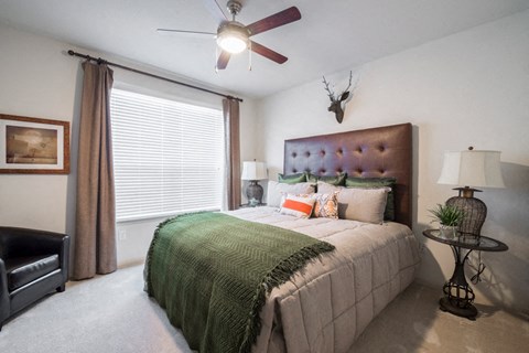 A bedroom with a bed, a chair, and a ceiling fan.