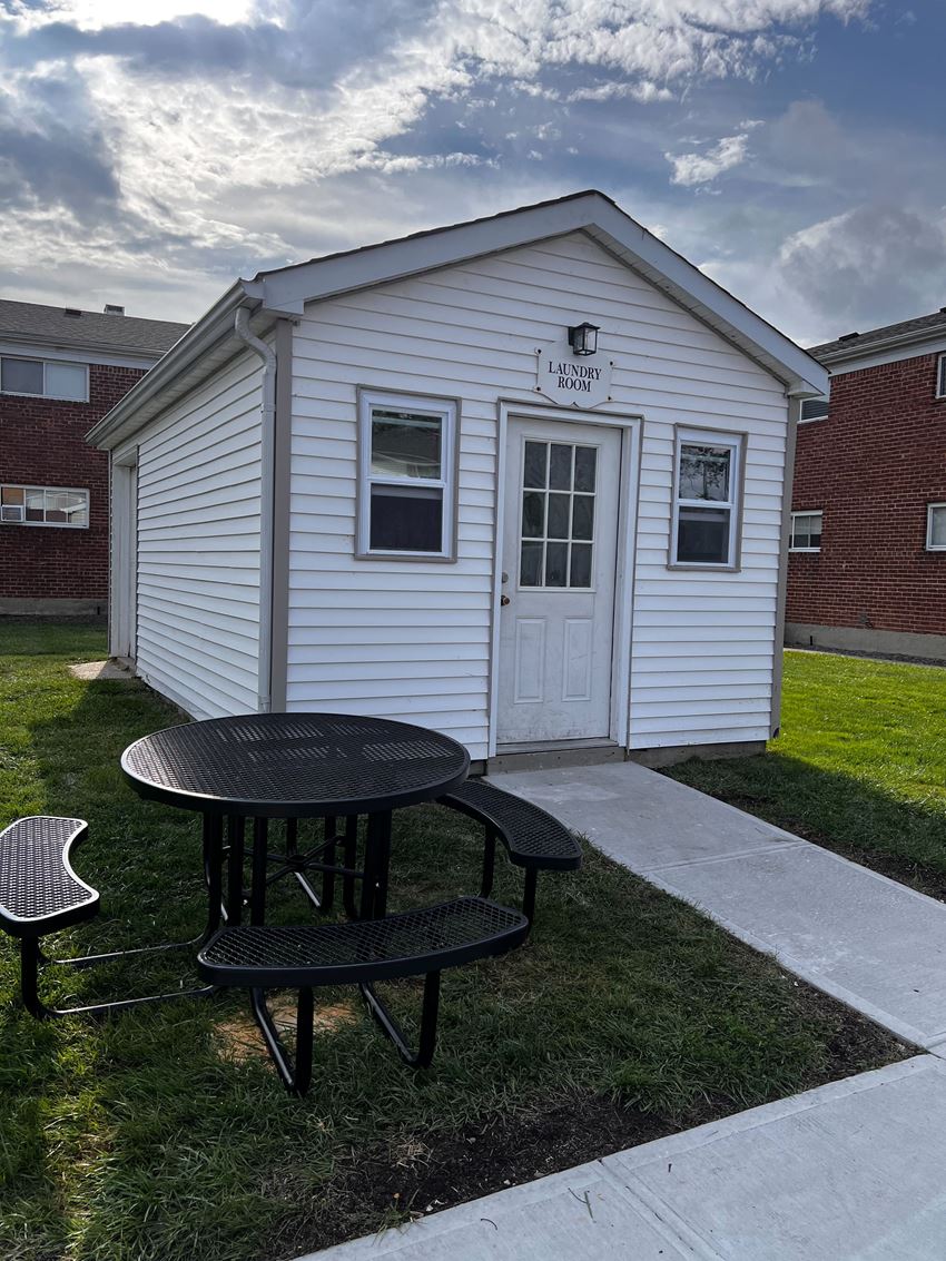 a small white building with a table and chairs in front of it