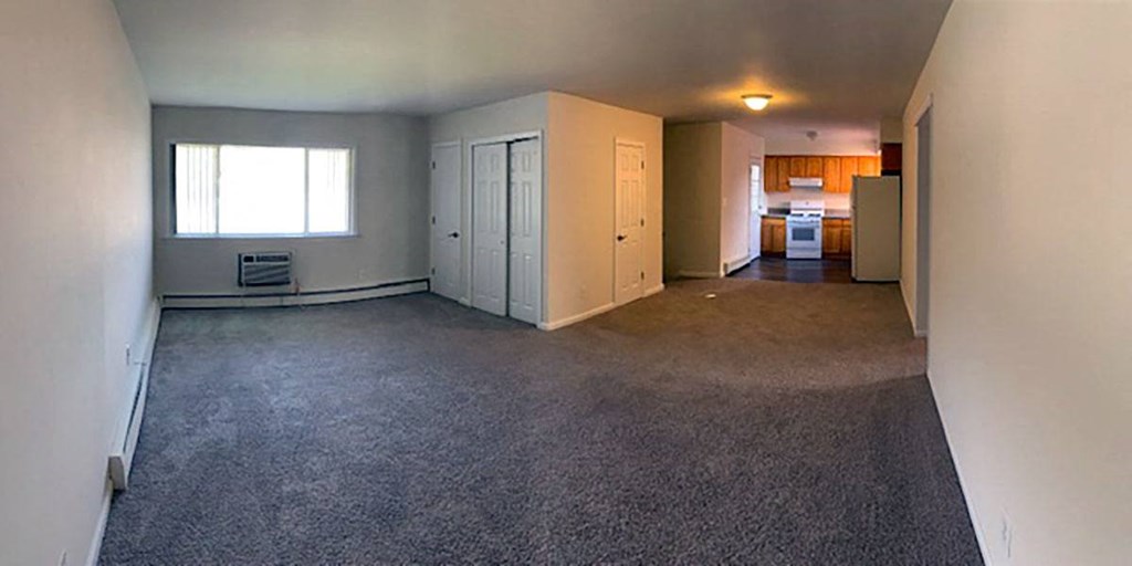 an empty living room with a kitchen in the background at Brookwood at Sayville, Sayville, NY, 11782