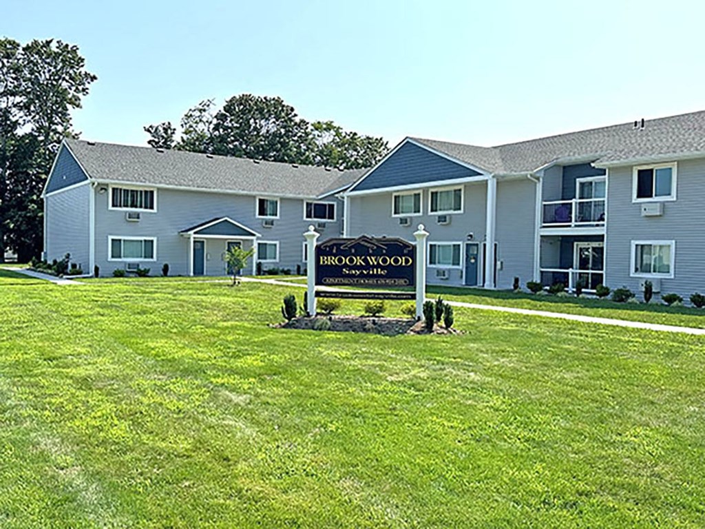 a large yard with a sign in front of a building at Brookwood at Sayville, New York