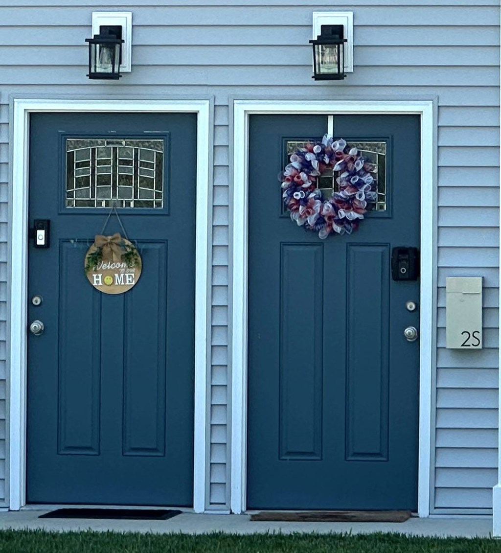 a pair of blue doors on a gray house with a purple wreath on the door at Brookwood at Sayville, New York