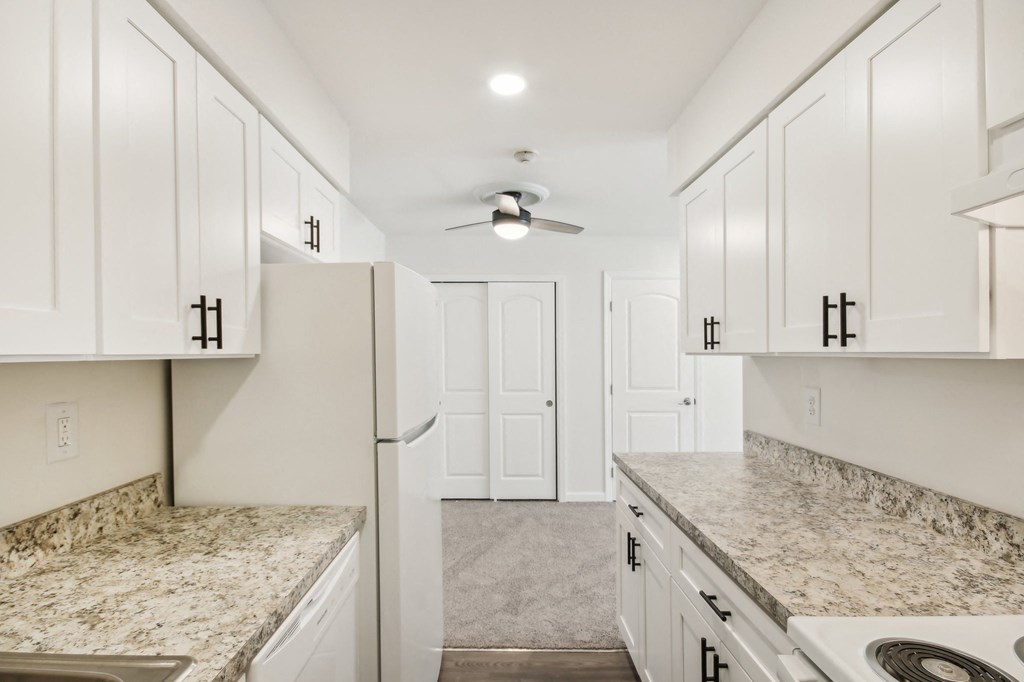 view of kitchen with white cabinets and granite counter tops and white appliances at Brookwood at Ridge, New York, 11961