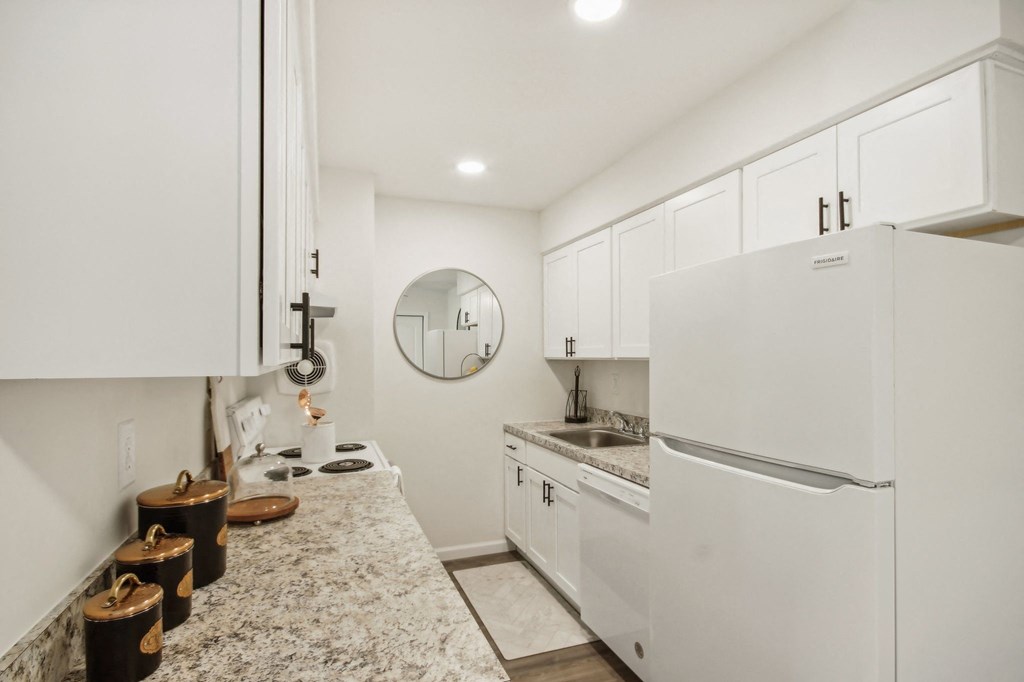 a beautiful white kitchen with white cabinets and a white refrigerator at Brookwood at Ridge, New York, 11961