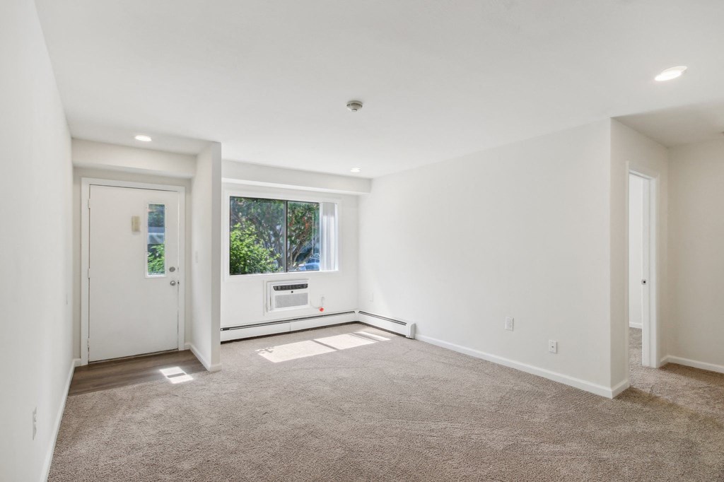 a view of living room with white walls and a window, front door and bedroom entrance at Brookwood at Ridge, New York, 11961