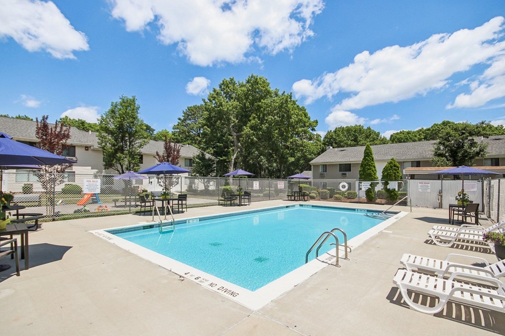 view of our sparkling swimming pool with chairs and umbrellas at Brookwood at Ridge, New York, 11961