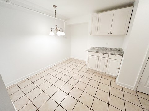 A kitchen with white cabinets and a marble countertop.