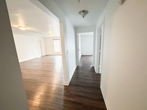 A long hallway with wood floors and white walls.