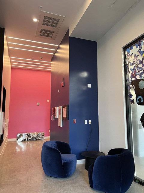 a living room with blue chairs and a red wall