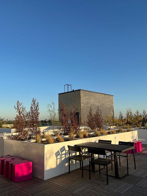 a rooftop patio with tables and chairs and a building in the background
