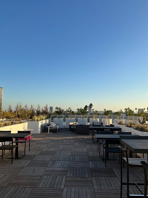 a roof terrace with tables and chairs and a blue sky