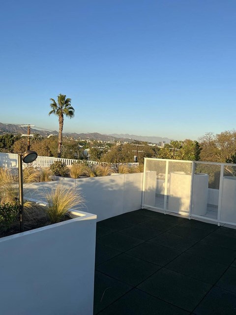 a roof terrace with a view of the city and palm trees
