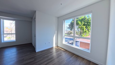 A room with a large window showing a view of a building and trees outside.