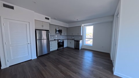 A kitchen with white cabinets and a stainless steel refrigerator.