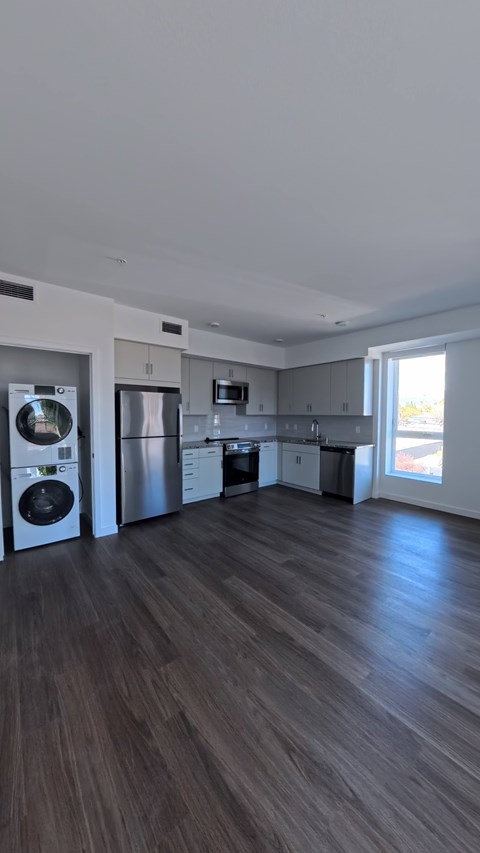 A spacious kitchen with dark wood flooring and modern appliances.