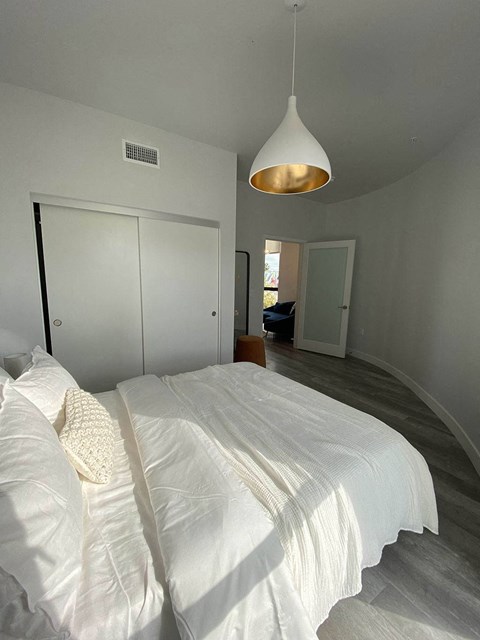 a white bed in a white bedroom with a lamp on the ceiling