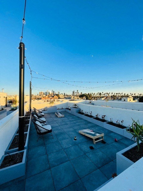 a rooftop terrace with lounge chairs and a view of the city