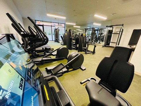a gym with cardio equipment and weights on the floor of a building