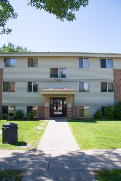 A building with a brown door and windows with trees in the background.