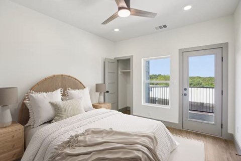 A bedroom with a bed, two lamps, and a ceiling fan.
