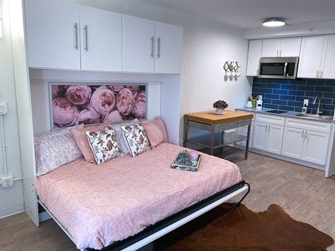 a bedroom with a bed and a kitchen with white cabinets