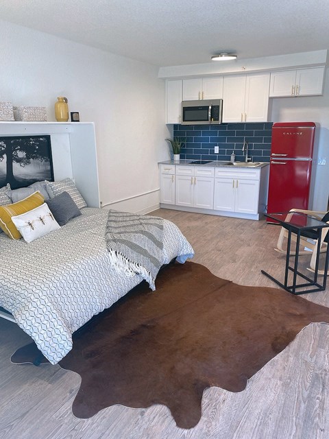 a bedroom with a bed and a kitchen with a red refrigerator