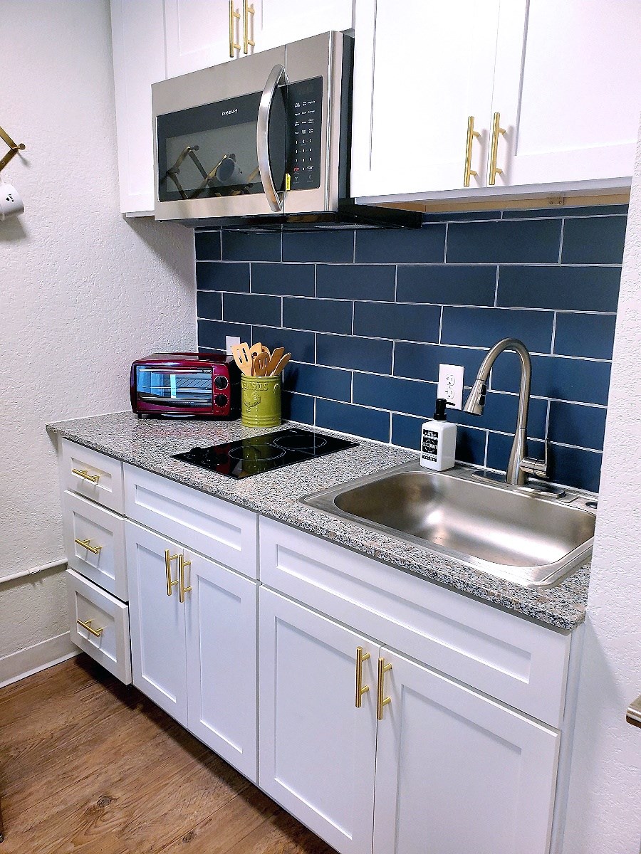 a kitchen with white cabinets and a sink and a microwave
