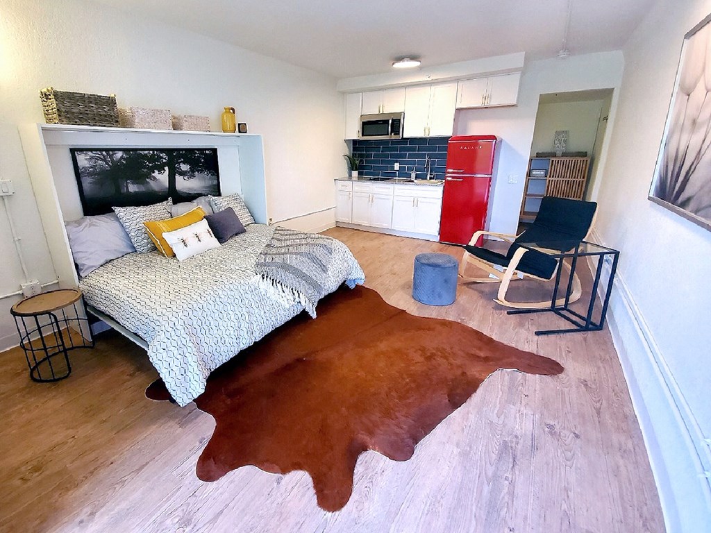 a bedroom with a bed and a kitchen with a red refrigerator
