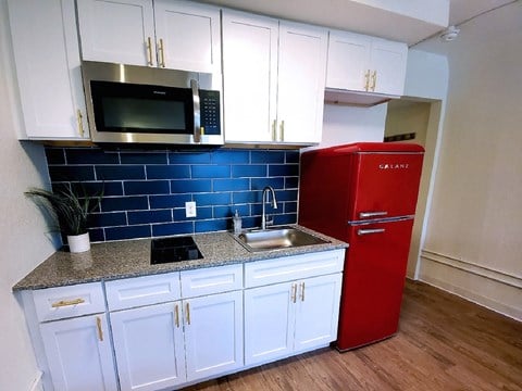 a kitchen with white cabinets and a red refrigerator