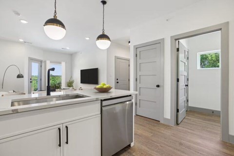 A modern kitchen with a stainless steel dishwasher and white cabinets.