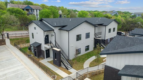 A white building with a black roof is surrounded by a parking lot.
