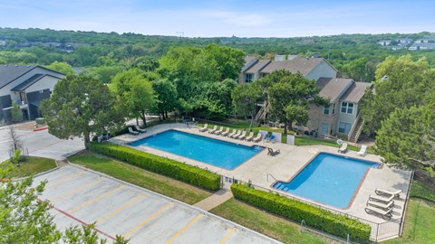 A large swimming pool surrounded by a grassy area and trees.