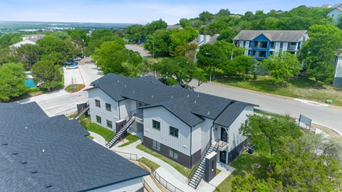 A large house with a grey roof is surrounded by trees.