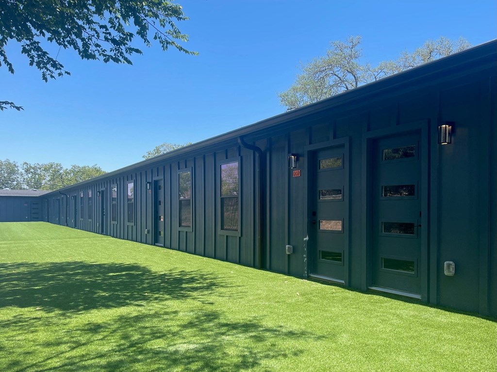 a row of barracks with green doors and grass